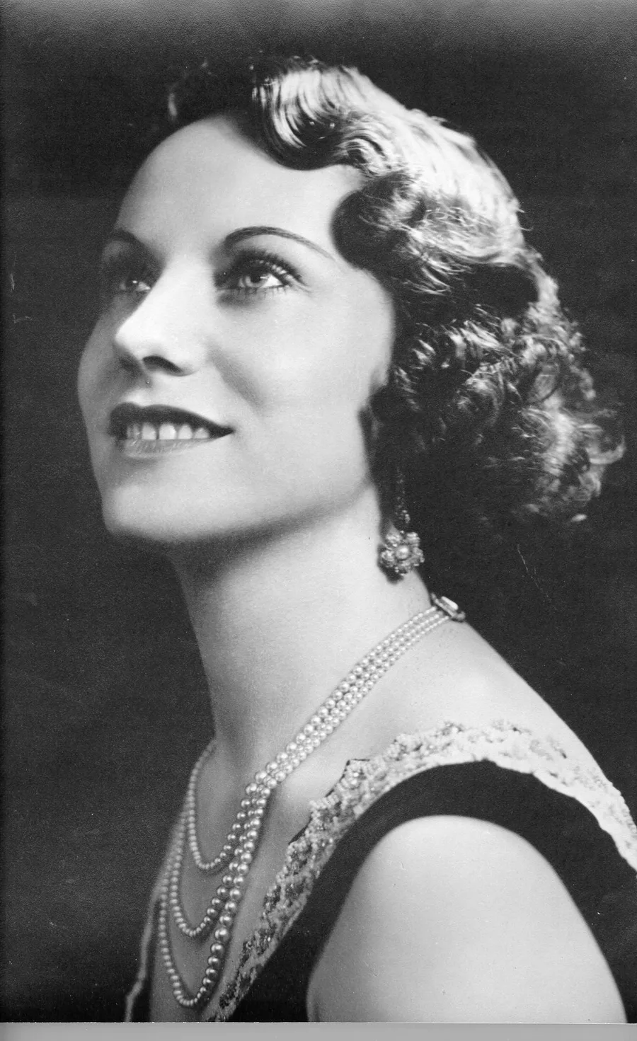 Studio portrait of Lao Russell wearing pearls, turned slightly toward the camera.